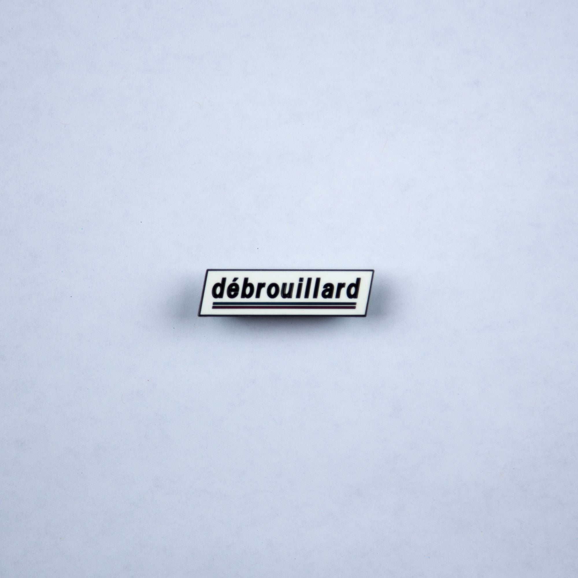 Débrouillard logo hard enamel pin with a black rubber clutch backing.